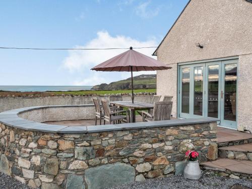 um pátio com um guarda-sol, uma mesa e cadeiras em Stack View Cottage em Holyhead