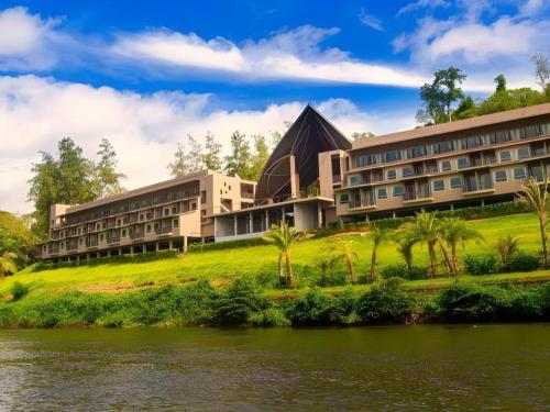 a building on a hill next to a river at River Kwai Village Hotel in Ban Kaeng Raboet