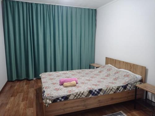 a bed in a room with a green curtain at Двухкомнатная квартира in Aktobe