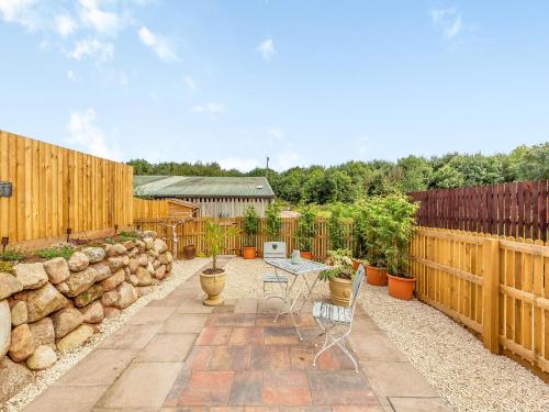a patio with a table and chairs and a fence at The Pigeons Nest in Peplow