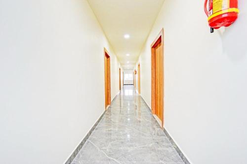 a corridor with white walls and a tile floor at Hotel O Kurnool City Railway Junction Formerly Diamond Court in Kurnool