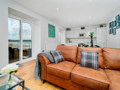 sala de estar con sofá marrón y cocina en No 2 Sunnyside Apartments, en Woolacombe