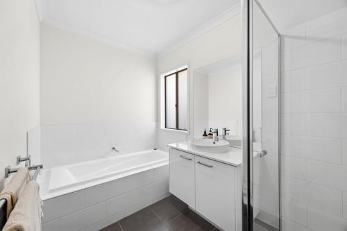 a white bathroom with a sink and a bath tub at Roberts Retreat in Torquay