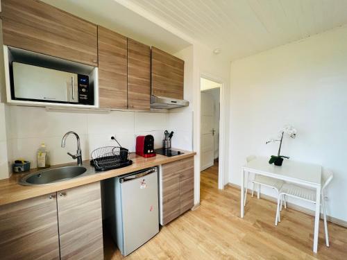 a kitchen with wooden cabinets and a sink and a table at Charmants logements au centre ville de Rosny Sous Bois in Rosny-sous-Bois