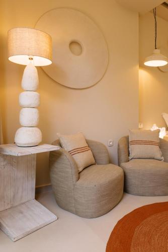 a living room with a chair and a lamp at Sea Nymphs Suites in Agia Anna Naxos