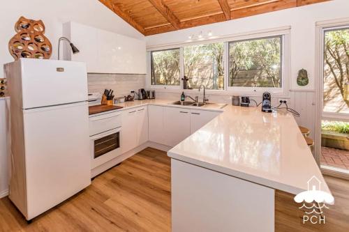 a kitchen with white appliances and a wooden ceiling at Banksia Beauty in Sandy Point