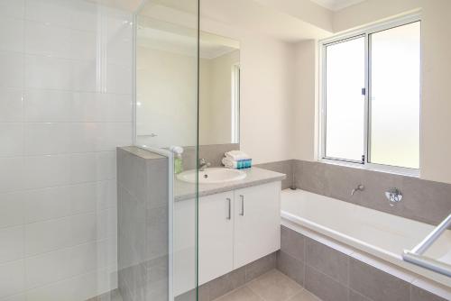 a white bathroom with a sink and a tub and a window at Dunsborough Sunrise in Dunsborough