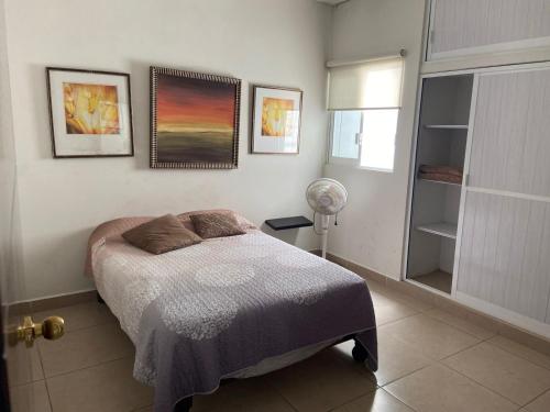 a bedroom with a bed and two pictures on the wall at Lomas de Mazatlán in Mazatlán
