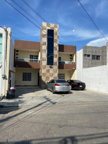 two cars parked in a parking lot in front of a building at Lomas de Mazatlán in Mazatlán