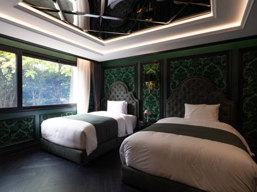 two beds in a room with green walls and windows at The Siena PRIMO in Seogwipo