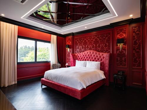 a red bedroom with a large bed with a red headboard at The Siena PRIMO in Seogwipo