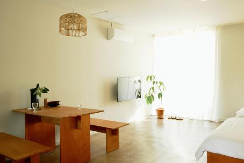 a living room with a wooden table and a bed at Pyoseon Mansion in Seogwipo