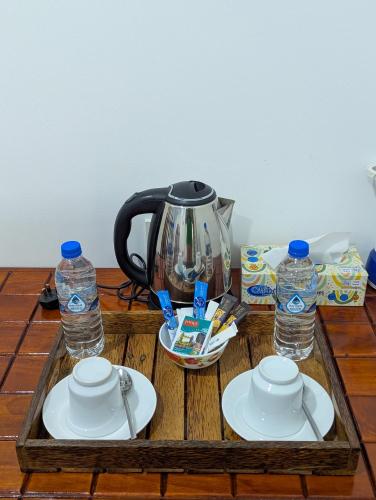 a tea kettle and two bottles of water on a wooden table at Nehansa Resort and safari in Tissamaharama