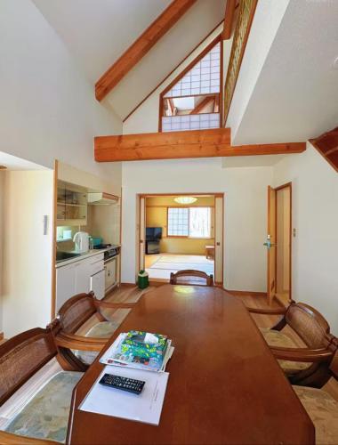 a room with a table with a keyboard and a kitchen at 軽井沢七福荘ホテル in Tsumagoi