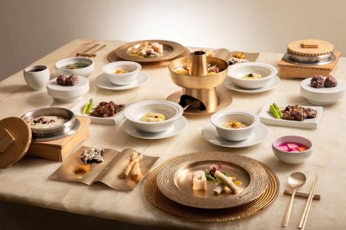 a table topped with plates and bowls of food at The Siena PRIMO in Seogwipo