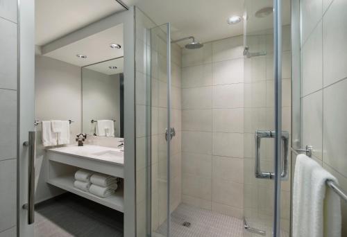 a bathroom with a shower and a sink and a mirror at Norwood Hotel in Winnipeg