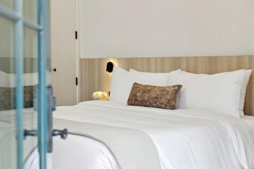 a large bed with white sheets and a pillow at Casa Riviera - Boutique Suites in Downtown Santa Barbara in Santa Barbara