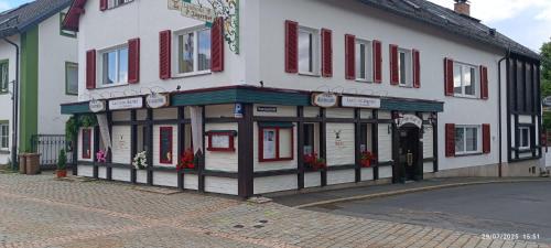a white building with red windows on a street at Landhotel Jägerhof in Bischofsgrün