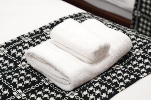 a stack of towels sitting on top of a bed at Nihonbashi Royal in Osaka