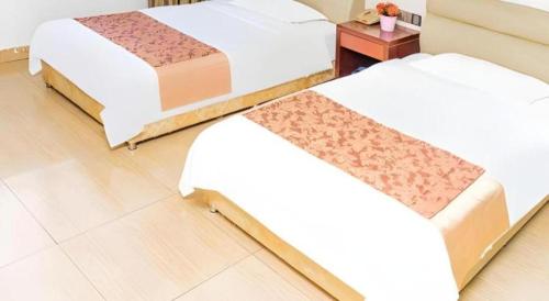 a room with three beds and a table with a night stand at Jian Guo Grand Hotel in Vientiane