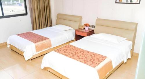 a hotel room with two beds and a night stand at Jian Guo Grand Hotel in Vientiane