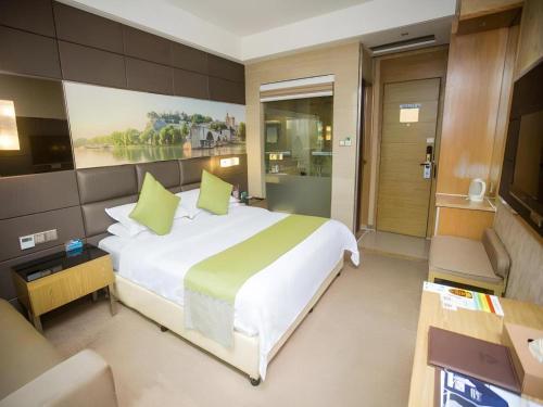 a bedroom with a large white bed with green pillows at GreenTree Alliance Shenzhen Shekou Sea World Hotel in Shenzhen