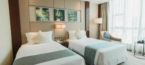 a hotel room with two beds and a window at Grand Soluxe Zhongyou Hotel Shenzhen in Shenzhen