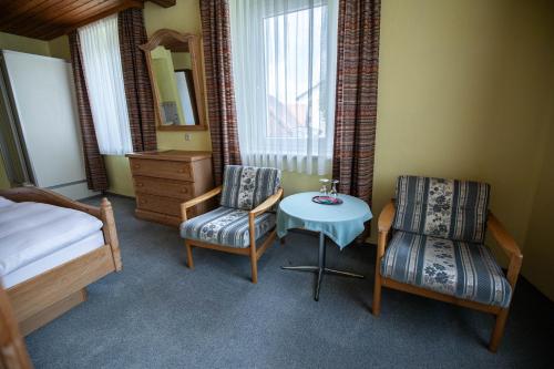 a bedroom with a bed and a table and two chairs at Landhotel Jägerhof in Bischofsgrün