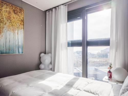 a bedroom with a bed and a large window at Vourne Osiria in Busan