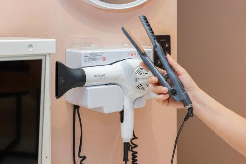a person holding a blow dryer on a wall at 호텔 데일리 안산 in Ansan