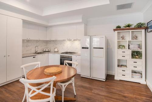 a kitchen with a wooden table and white appliances at Lazy Daze Beach House in Quindalup