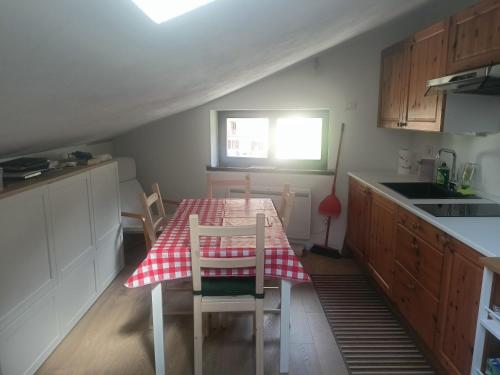 a kitchen with a table with a red and white checkered table cloth at La mansarda in Valmalenco in Chiesa in Valmalenco