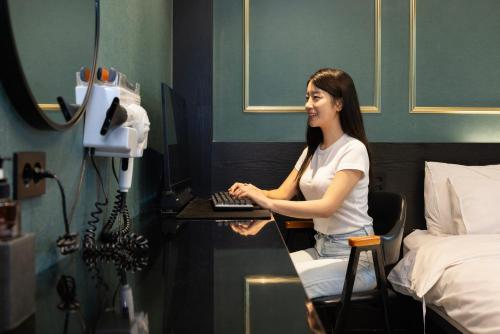 a woman sitting at a desk with a computer at 호텔 데일리 안산 in Ansan