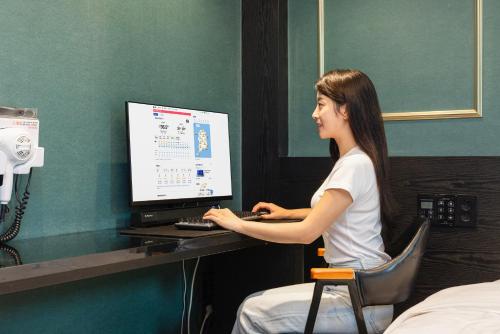 a woman sitting at a desk with a computer at 호텔 데일리 안산 in Ansan