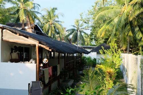 a house with a black roof and palm trees at Skott's Comfy Lodge in Bantayan Island