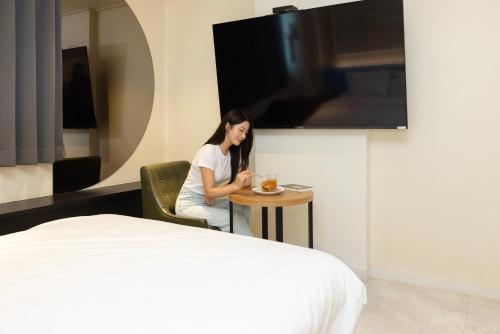 a woman sitting at a table in a hotel room at 호텔 데일리 안산 in Ansan