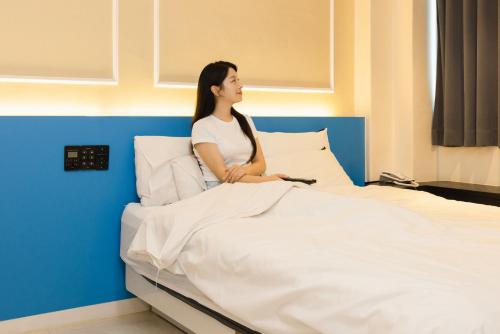 a woman sitting on top of a bed at 호텔 데일리 안산 in Ansan