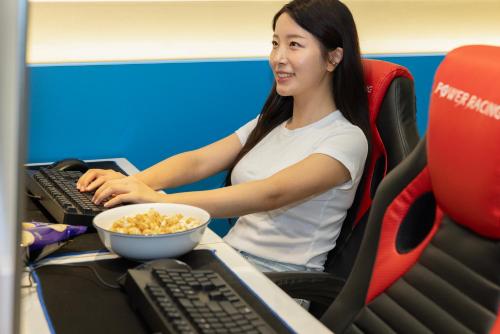 a woman sitting at a computer with a bowl of cereal at 호텔 데일리 안산 in Ansan