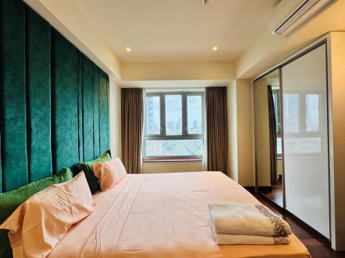Un dormitorio con una cama grande con una pared verde. en Welcome to Your 5-Star Stay at Cinnamon Life Suite, en Colombo