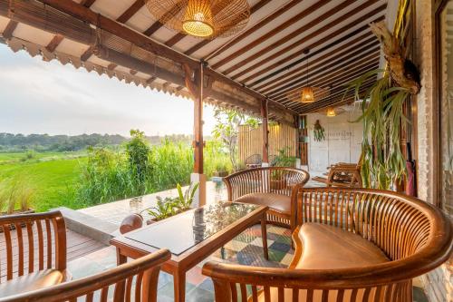 a porch with wooden chairs and a table and a view at Villa Sare - House with panorama rice field view in Yogyakarta