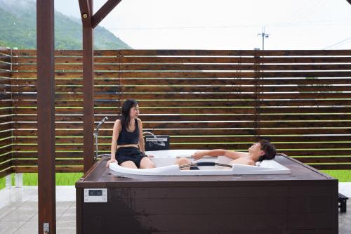 a man and a woman sitting in a hot tub at Resoreat Shirahige in Takashima