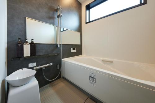 a bathroom with a tub and a toilet and a sink at Resoreat Shirahige in Takashima