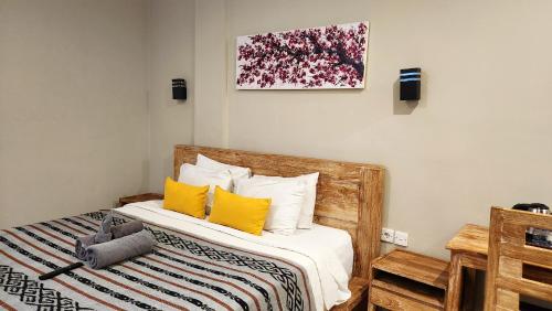 a bedroom with a wooden bed with yellow pillows at Olivia Guest House Canggu in Canggu