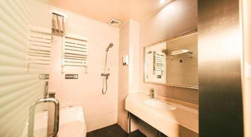 a white bathroom with a sink and a mirror at 7 Days Inn Harbin Medical University First Affiliated Hospital in Harbin