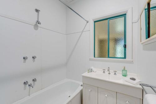 a white bathroom with a tub and a sink at Just the Spot in Myrtleford