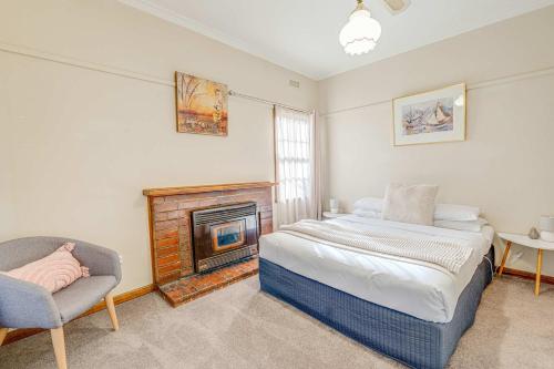 a bedroom with a fireplace and a bed and a chair at Just the Spot in Myrtleford