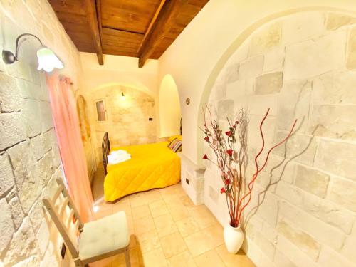 Un dormitorio con una cama amarilla en una pared de piedra. en Trulli Bovio, en Alberobello