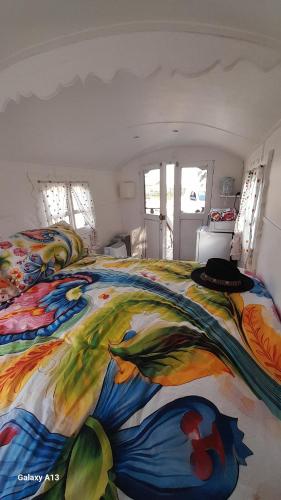 a bedroom with a colorful blanket on a bed at La roulotte au bord de l'étang 