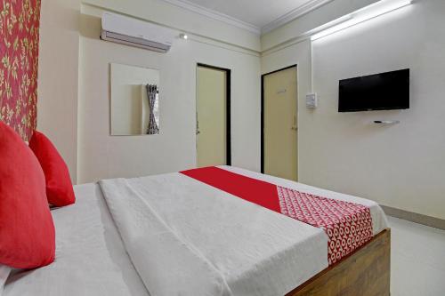 a bedroom with a bed with red pillows and a tv at Hotel O Sai Executive Lodging in Māngvādi