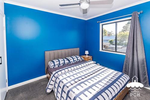 a blue bedroom with a bed and a window at Fishermans Stay 